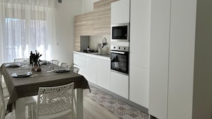 Una cocina moderna con armarios blancos, microondas integrado y horno.