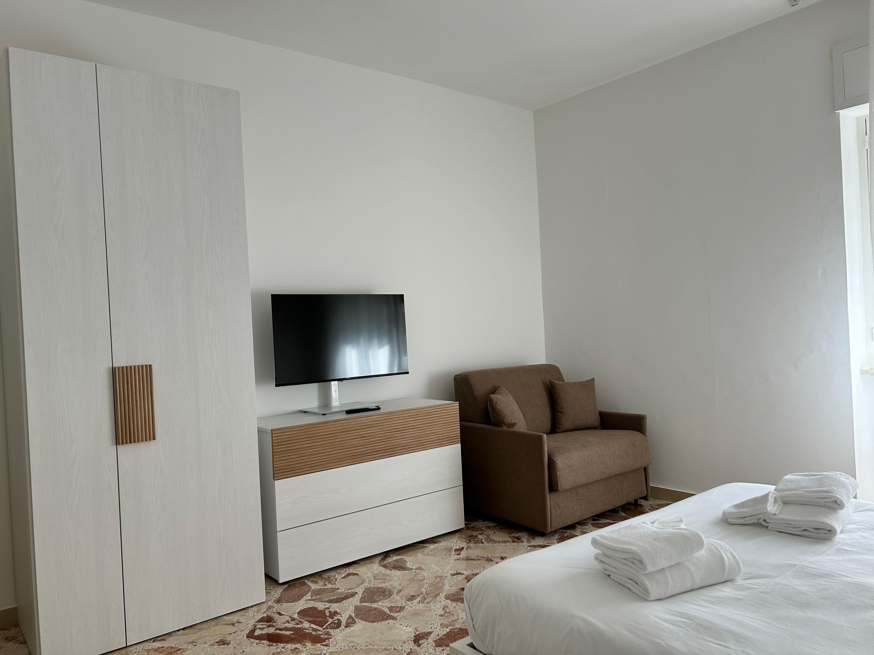 A bedroom with a bed, a TV, a sofa, and a wardrobe.