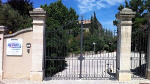 Une entrée fermée par un portail, avec une pancarte indiquant qu’il s’agit d’un site historique.