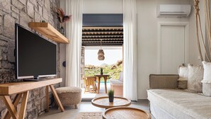 Ein Wohnzimmer mit Fernseher, Holzmöbeln, einer Steinwand und Blick ins Freie.
