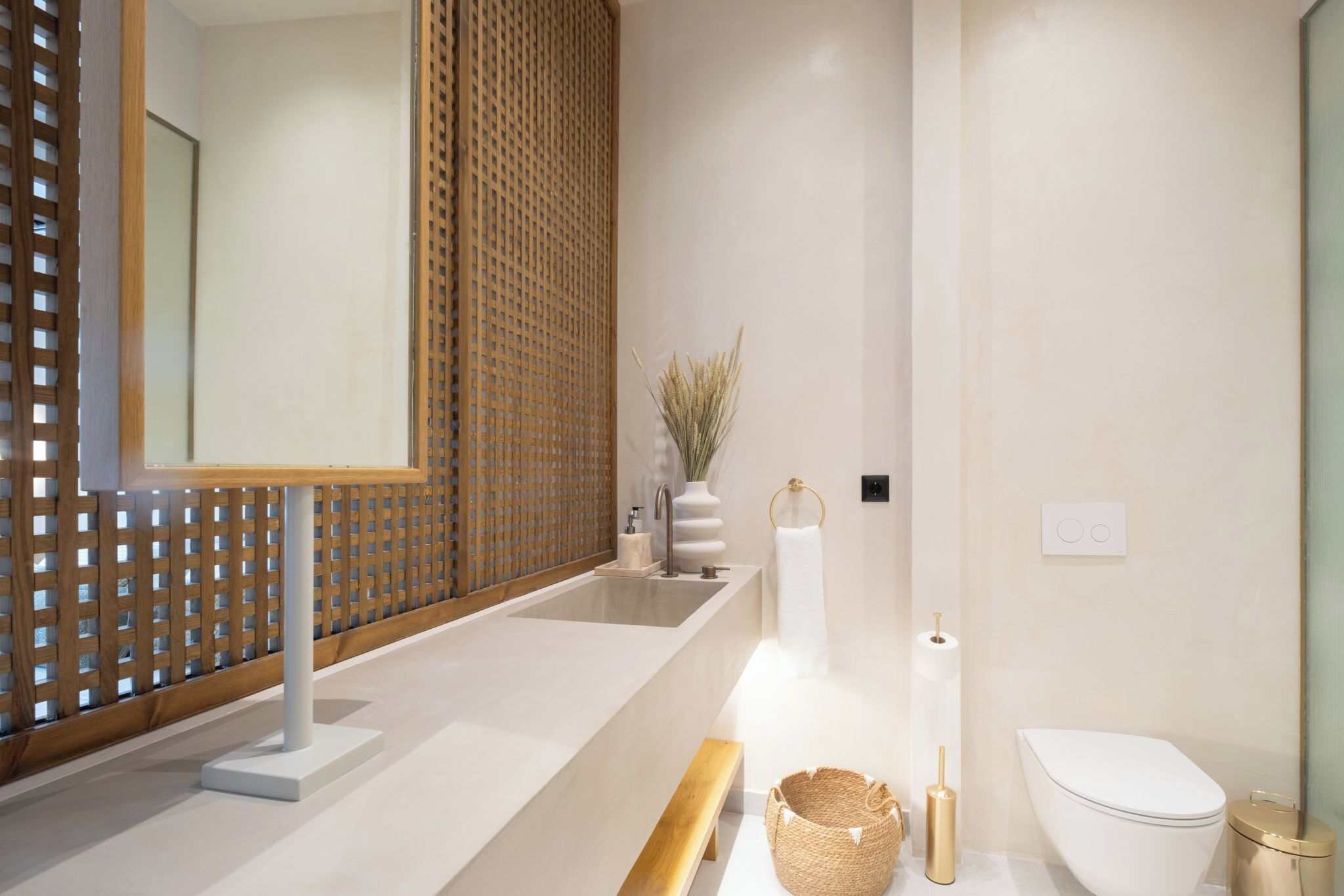 Une salle de bain moderne avec un grand miroir, un lavabo, des toilettes et un banc en bois.