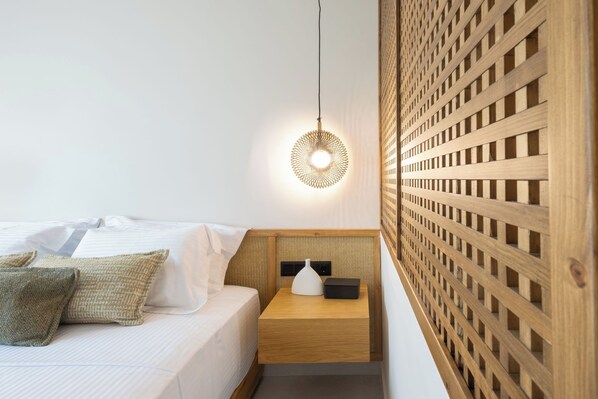 A hotel room with a bed, a bedside table with a lamp, and a wooden partition wall.