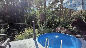 A swimming pool with a wooden deck, surrounded by trees and a rock formation. - Escape to Luxury in the Cangrejal River Valley – A Jungle Retreat Awaits! (Atlántida Department)