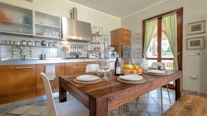 A modern kitchen with wooden cabinets, a stainless steel range hood, and a dining area with a wooden table set for four.