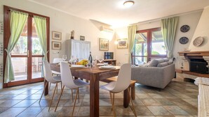 A dining area with a wooden table and chairs, a sofa, and a fireplace.