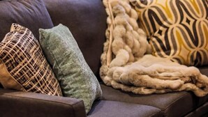 A dark brown sofa with three decorative pillows and a thick, textured blanket. - YOUR HOME-pooltable-playset-sauna (Willmar)