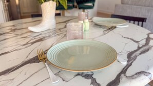 Een marmeren eettafel met een groen bord, een gouden vork en een witte lepel.
