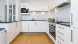 Et moderne køkken med hvide skabe, indbygget mikroovn og en ovn i rustfrit stål.