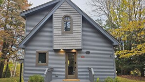 A two-story house with a gabled roof, a front door, and a small porch with steps.