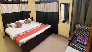 Une chambre à coucher comprenant un lit, un bureau, une chaise, un ventilateur de plafond et des rideaux.