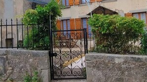Ein zweistöckiges Haus mit geschlossenem Eingangstor, einer kleinen Veranda und einer sichtbaren Treppe zum Eingang.
