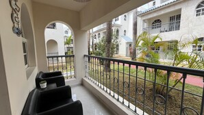 En balkon med udsigt over en gård, med gelænder og et par stole.
