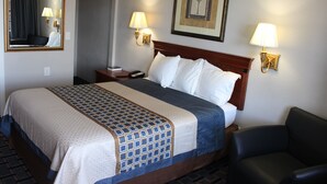 Ein Hotelzimmer mit einem Bett, einem Nachttisch, einem Sessel, einem Schreibtisch und zwei Wandlampen.