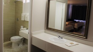 Ein Hotelbad mit Dusche, Toilette, Waschbecken und einem großen Spiegel.
