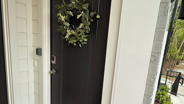 A black door with a wreath, a welcome mat, and a house number 100. -  BRAND NEW Condo in HISTORIC Downtown Wake Forest (Wake Forest)
