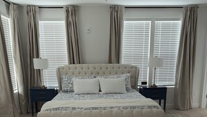 A bedroom with a large bed, two bedside tables, a ceiling fan, and a window with curtains. -  BRAND NEW Condo in HISTORIC Downtown Wake Forest (Wake Forest)