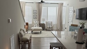A spacious living area with a large dining table, multiple chairs, a sofa, and a TV mounted on the wall. -  BRAND NEW Condo in HISTORIC Downtown Wake Forest (Wake Forest)