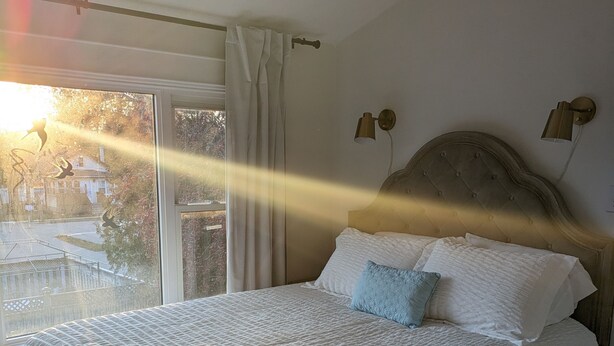 A bedroom with a large bed, a window with curtains, and a view of the outside. - Cozy retreat home in Guelph. Pet-friendly! (Guelph)