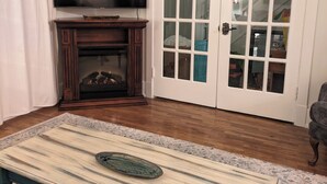 A living room with a fireplace, a television, and a door with glass panels. - Cozy retreat home in Guelph. Pet-friendly! (Guelph)