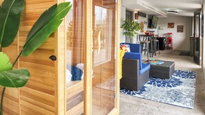 A wooden sauna room with a glass door, a blue sofa, and a patterned rug in a modern living area.
