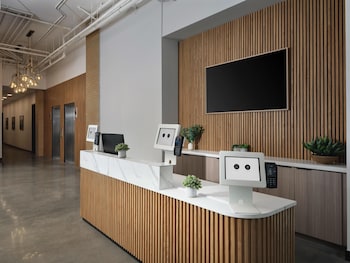 A modern kitchen with a stainless steel refrigerator, a built-in oven, a coffee maker, and a washing machine. at The Margot Hotel San Diego Gaslamp Quarter, Outset by Hilton