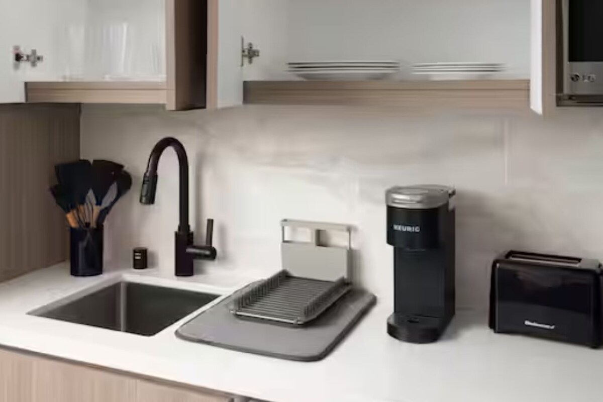 Ett modernt kök med en diskho, en kaffemaskin, en brödrost och ett knivställ.