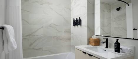 Ein modernes Badezimmer mit einer Badewanne, einem Waschbecken mit Toilettenartikeln und einem Spiegel.