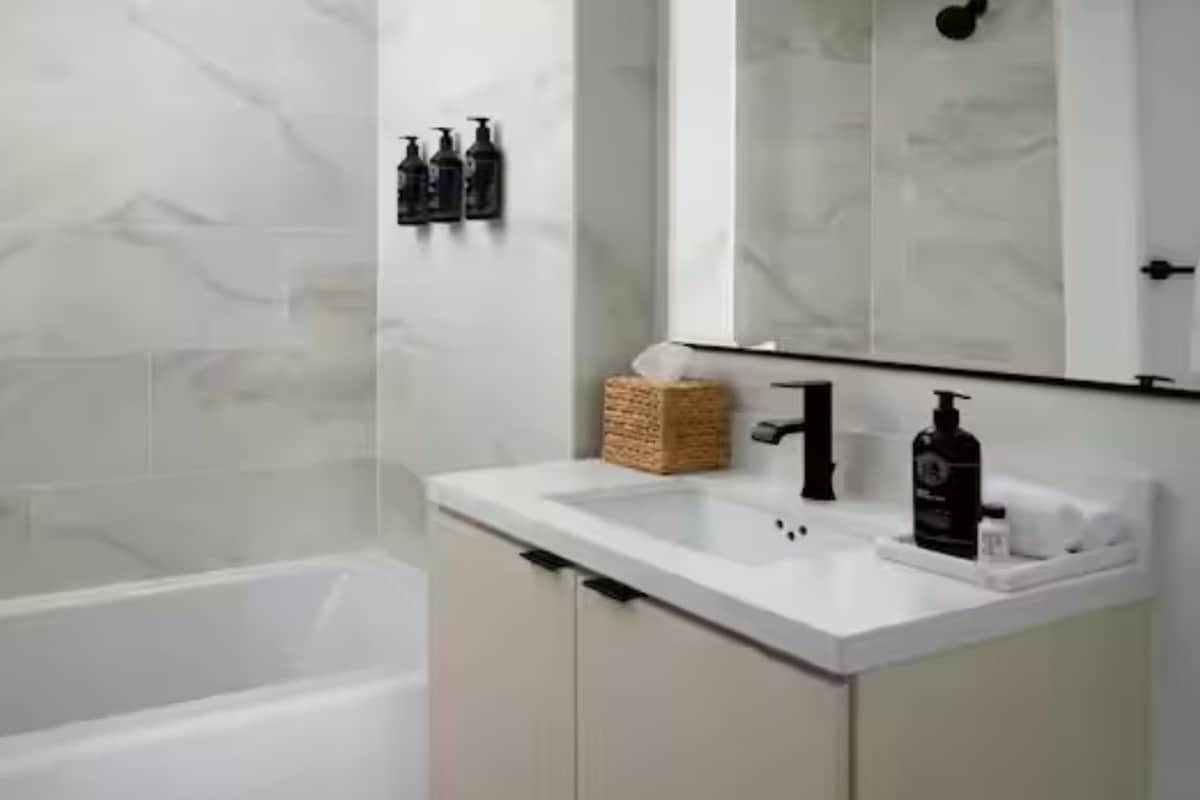 Un baño con una bañera blanca, un lavamanos blanco y un espejo sobre el lavamanos.