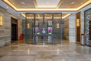 A spacious lobby with a decorative partition, a reception desk, and a potted plant. - Tabao Garden (Chongqing)