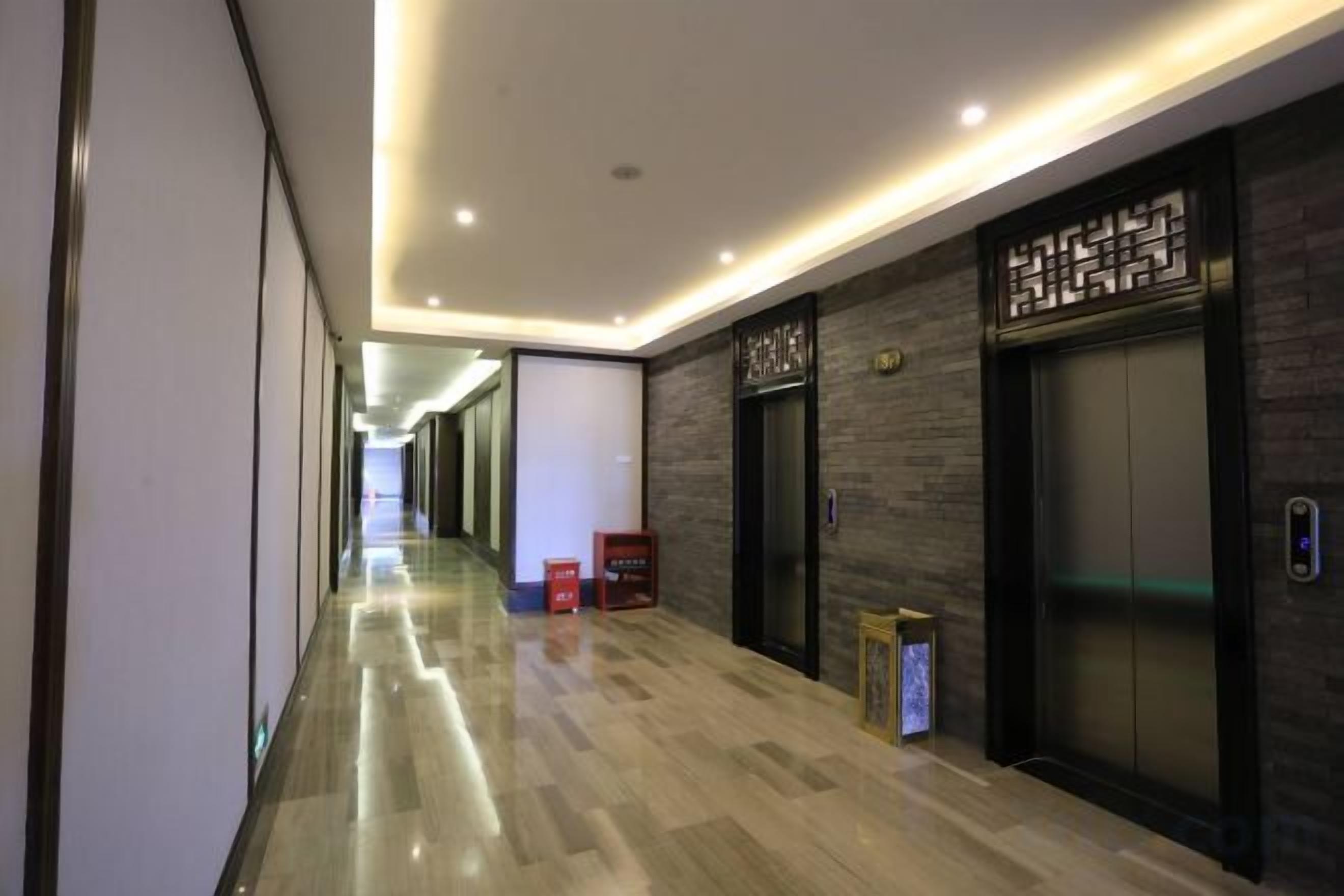 A hotel corridor with a polished floor, a reception desk, and an elevator.