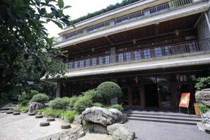 A traditional multi-story building with a courtyard, featuring a wooden balcony, stone steps, and potted plants. - Tabao Garden (Chongqing)