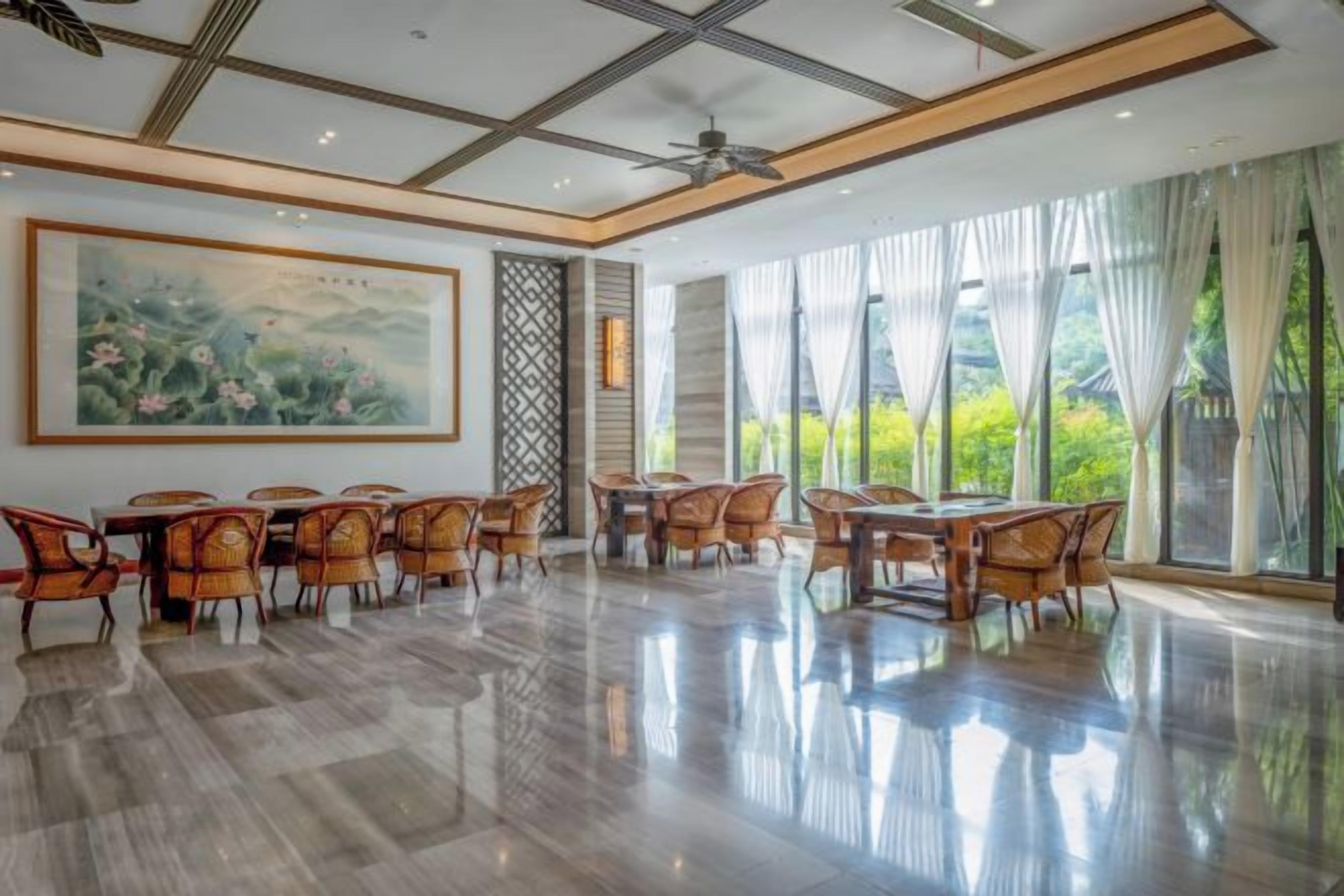 A spacious dining area with a polished floor, large windows, and a ceiling fan.