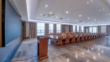 A conference room with a long table, chairs, a podium, and a large screen.