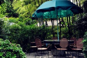 An outdoor seating area with a round table and chairs, surrounded by lush greenery. - Tabao Garden (Chongqing)