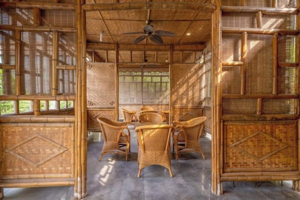 A room with a ceiling fan, bamboo furniture, and a view through the window. - Tabao Garden (Chongqing)