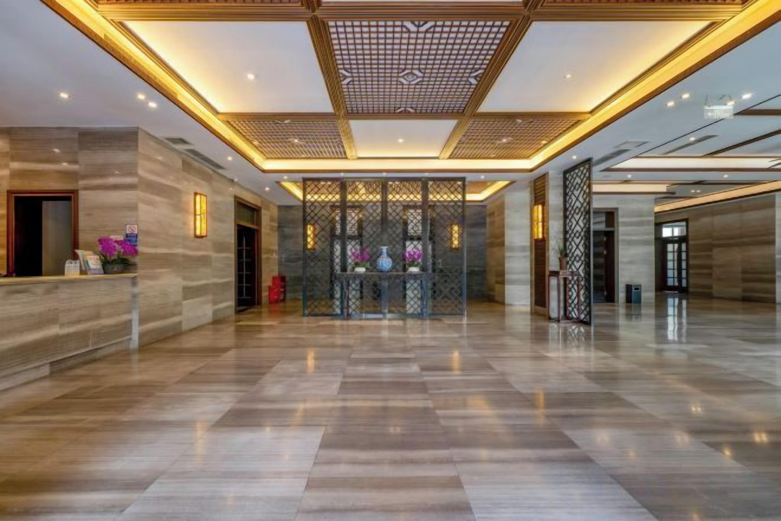 A spacious lobby with a polished marble floor, a reception desk, and a decorative partition with a geometric pattern.