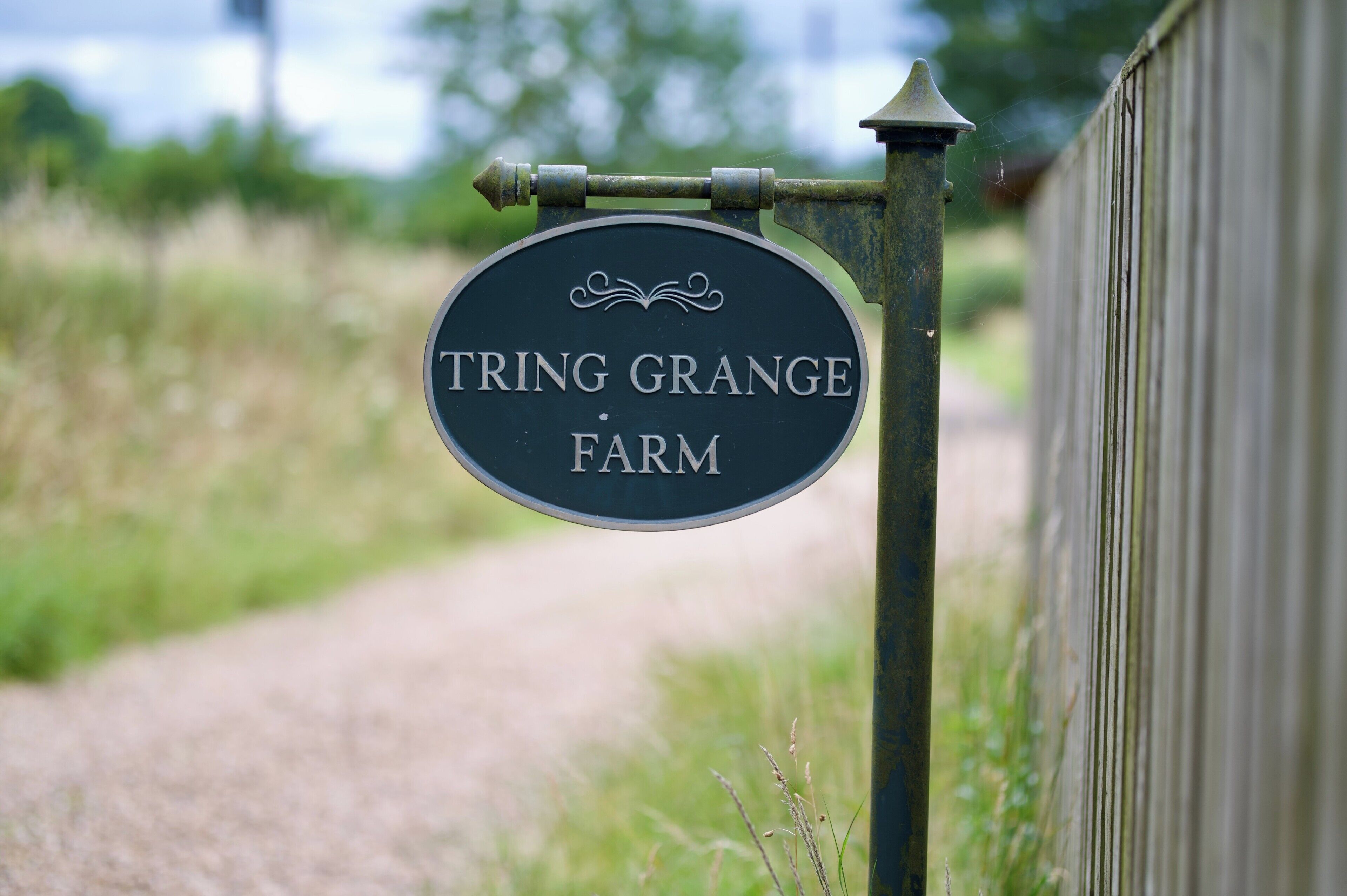 Ein Schild mit der Aufschrift 'TRING GRANGE FARM' an einem Pfosten befestigt.