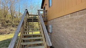 A wooden staircase leading to a building with a brick exterior. - Trailhead Riverfront Cabin (McCarr)