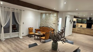 Ein modernes Wohnzimmer mit Esstisch, Ledersofas und einer Wand aus Stein.