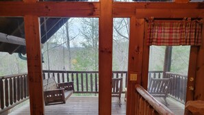 Eine Holzterrasse mit einer Schaukel, einer Bank und einem Geländer.