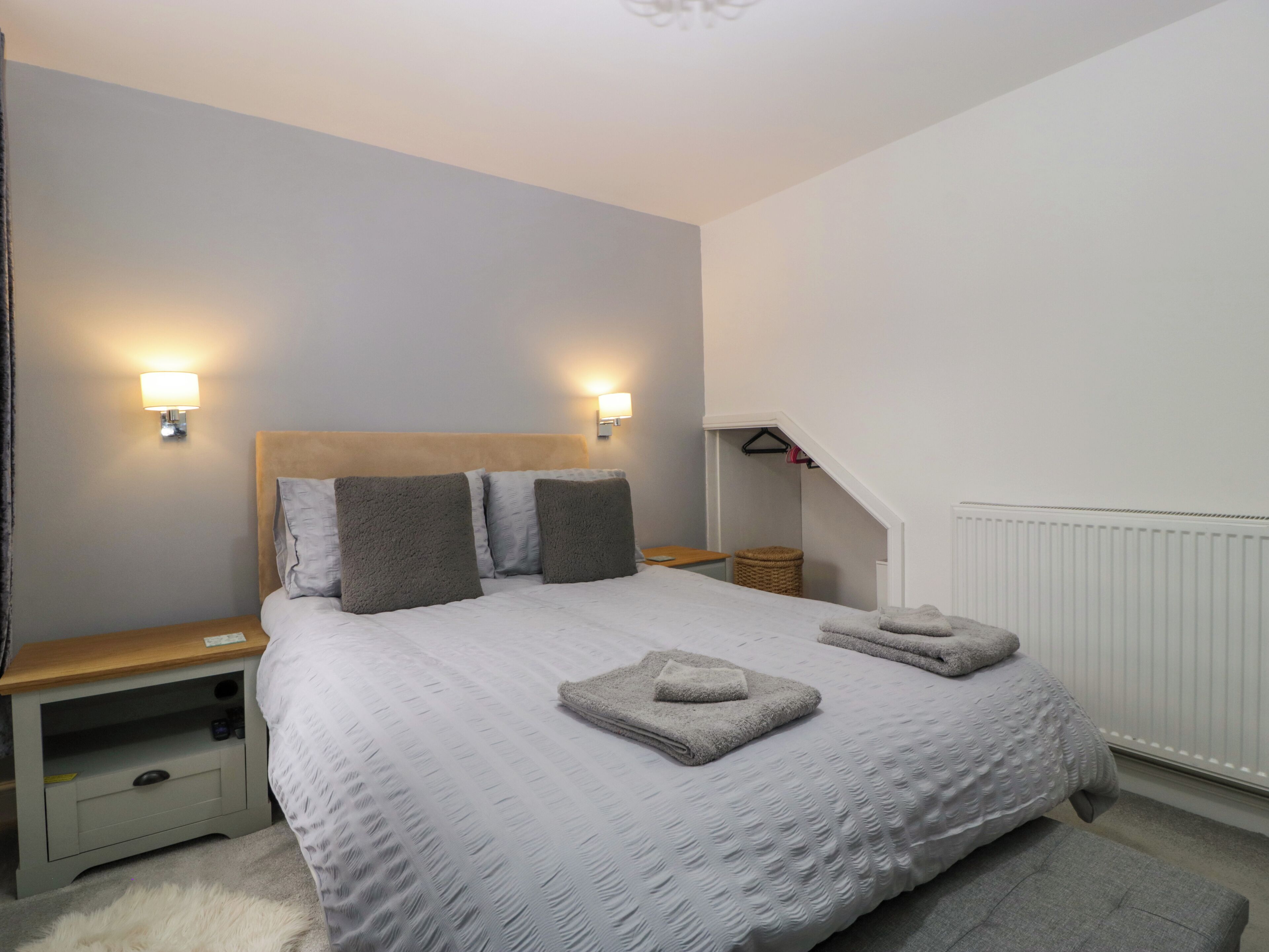 Une chambre à coucher avec un grand lit, deux tables de chevet, une commode, une lampe et un radiateur.