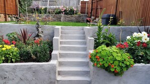 A concrete staircase leading up to a garden area with various plants and flowers. - Colliers Cottage (Cinderford)