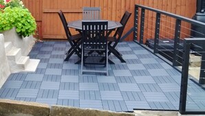A patio with a table and chairs, a wooden fence, and a metal railing. - Colliers Cottage (Cinderford)