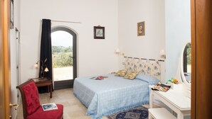 Un dormitorio con cama, una silla, un escritorio y una ventana con vistas.