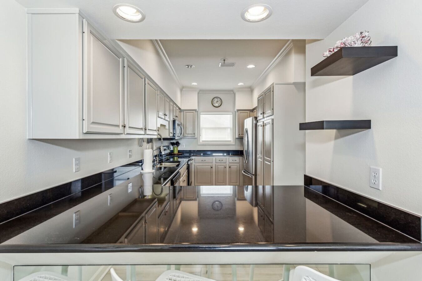 A modern kitchen with stainless steel appliances, white cabinetry, and black countertops.