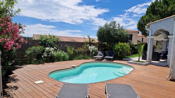 A wooden deck with a swimming pool, two lounge chairs, and a pergola.
