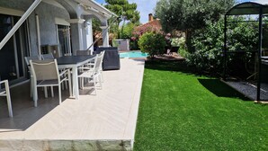 A patio area with a pool, outdoor furniture, and a well-maintained lawn.