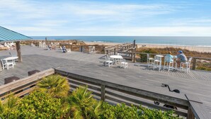 A wooden deck with outdoor seating and a view of the beach. - Family-friendly Villa by Ocean.  Walk to beach, bike, golf, tennis, fish & pool. (Pawleys Island)