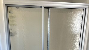 Una ventana con un diseño de vidrio esmerilado, dividida en cuatro secciones por marcos de metal.