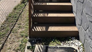Un conjunto de escaleras exteriores de madera que conducen a una casa con fachada de pared de piedra.